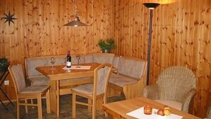 Et rum med træpaneler, et spisebord, to stole, en sofa og en gulvlampe.