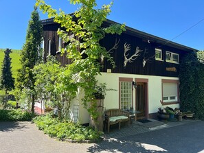 Ein zweistöckiges Gebäude mit Gartenanlage, einer Bank und einer Schaukel.