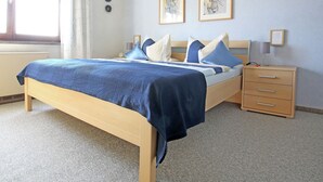 A neatly arranged bedroom with a bed, bedside tables, and artwork on the wall.