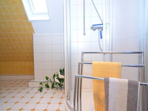 A modern bathroom with a glass shower enclosure, a yellow towel, and a small plant. - Ferienwohnung in Wehrstapel (Meschede)