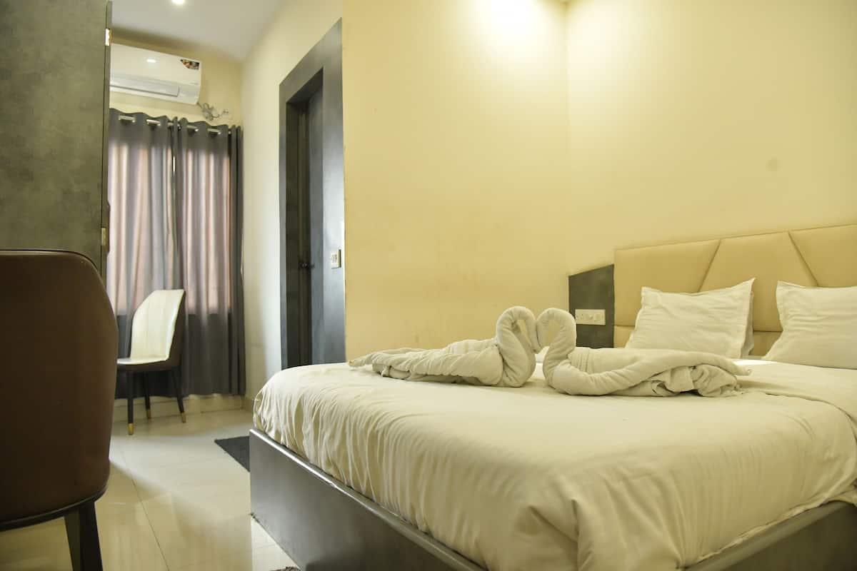 A hotel room with a bed, a chair, and a door.