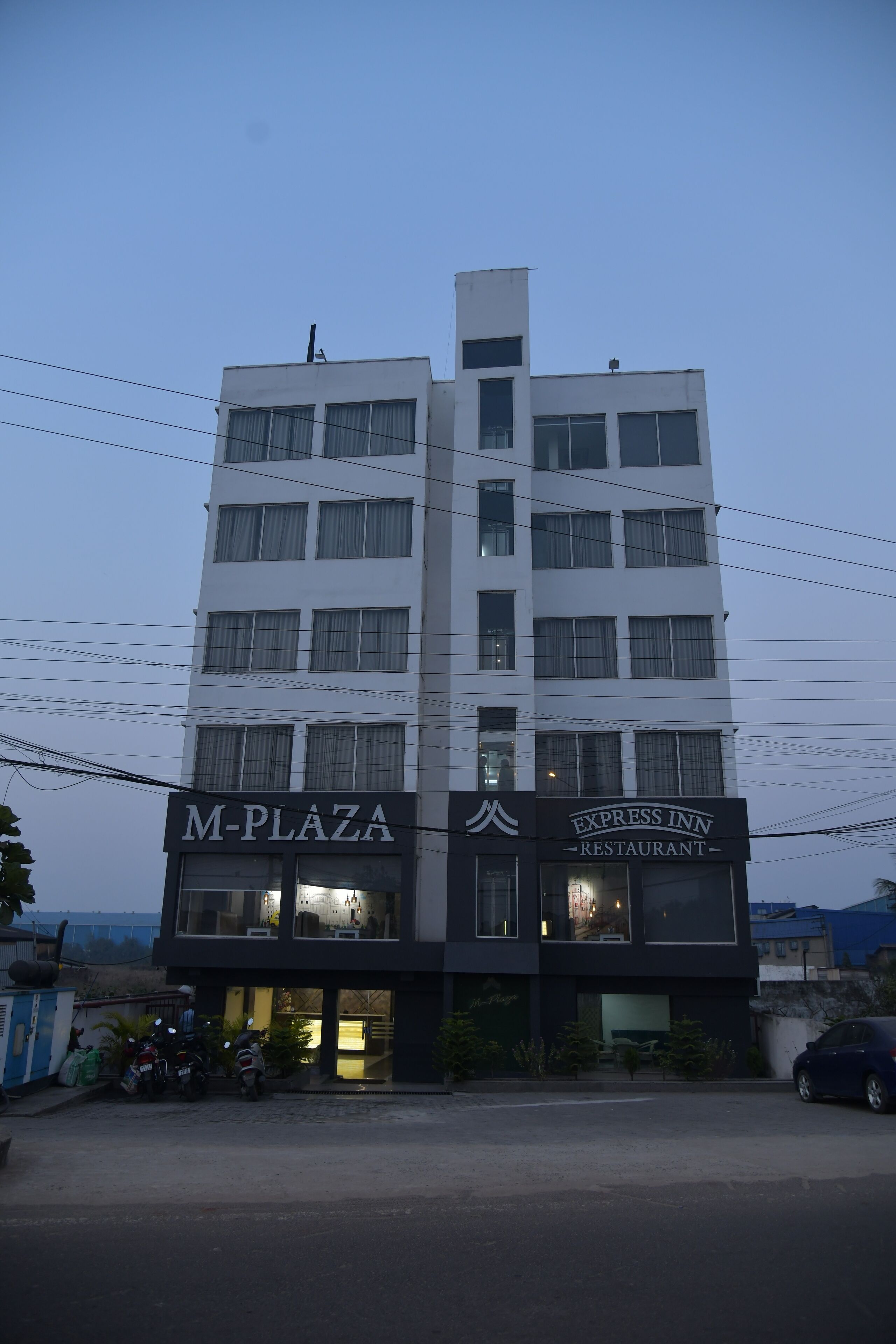 Un edificio de varios pisos con señalización que dice 'M-PLAZA' y 'EXPRESS INN RESTAURANT'.