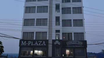 Un edificio de varios pisos con señalización que dice 'M-PLAZA' y 'EXPRESS INN RESTAURANT'.