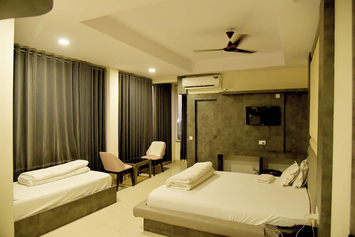 A hotel room with two beds, a chair, a TV, and an air conditioning unit.