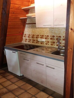 A compact kitchen with a dishwasher, a sink, and wooden cabinets.