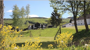 A rural setting with a large barn, a white building, and a grassy hill. - Charmantes Ferienhaus in Skigebietsnähe (Bestwig-Untervalme)