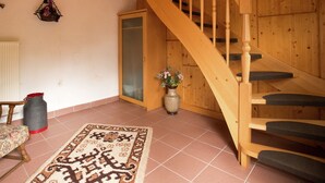 A wooden staircase with a glass door, a patterned rug, a wooden table, and a vase with flowers. - Ferienwohnung Oberschledorner Wald (Medebach)