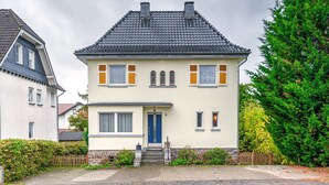 A two-story house with a dark tiled roof, a blue front door, and a small front porch. - Spacious Villa near Center (Medebach)