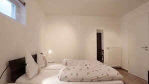Ein Schlafzimmer mit Bett, Nachttisch, Lampe und Fenster.