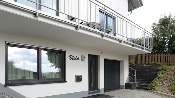Ein modernes Gebäude mit Balkon, großen Fenstern und einem Schild mit dem Schriftzug „Viola“.