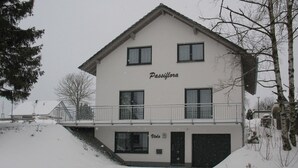Ein zweistöckiges Gebäude namens Passiflora mit einem Balkon und einer Garage.