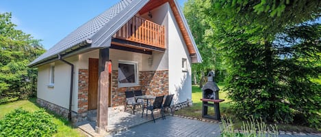 A two-story house with a balcony, a brick fireplace, and a paved patio.