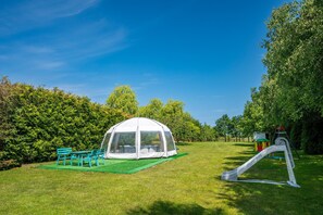 A tent with a transparent roof, a green lawn, and a playground with a slide. - Spacious and Comfortable Holiday Homes With Pool (Darlowo)