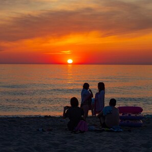 A sunset over the ocean with people sitting on the beach. - Spacious and Comfortable Holiday Homes With Pool (Darlowo)