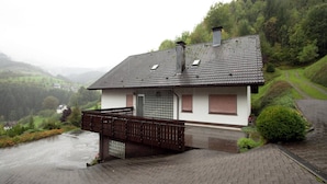 Une maison avec un toit en pente, un petit balcon et une allée pavée.