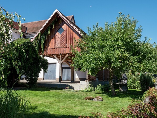 Ein traditionelles Holzhaus mit geneigtem Dach, einer Veranda und einem gepflegten Garten.