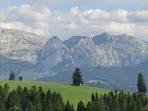 Un paysage de montagne avec une petite cabane sur une colline herbeuse.