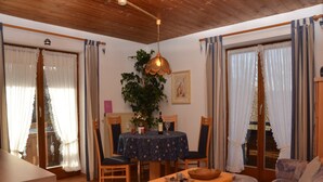 A cozy room with a wooden ceiling, a dining table with chairs, a sofa, and a small table with a bowl. - Ferienwohnung in Bad Bayersoien (Bad Bayersoien)