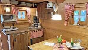 Eine rustikale Holz-Küche mit einem Holztisch, einer Kaffeemaschine und einer Champagnerflasche.