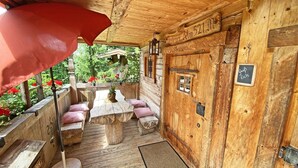A wooden cabin with a covered patio, a wooden table, and benches. - Bayerisches Refugium mit Sauna (Tittmoning)