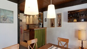 Una cocina acogedora con armarios de madera, una mesa de comedor con sillas e iluminación colgante.