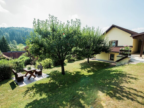 Una casa con giardino, un patio con tavolo e sedie, e vista sul paesaggio circostante.