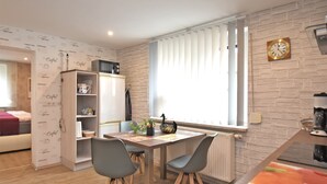 Una cocina moderna con comedor, que incluye una mesa de madera, dos sillas, un refrigerador y una ventana con persianas.