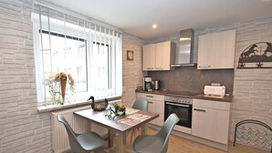 Una cocina moderna con una mesa de comedor, sillas y un ventanal con persianas.