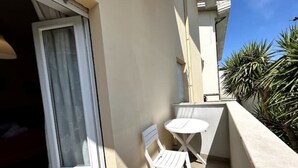 A balcony with a white chair and table, a window with curtains, and a palm tree in the background. - The "Cenerone" - Comfort and Relax, discover sea and country, feel our culture (Borgo Santa Maria Immacolata)