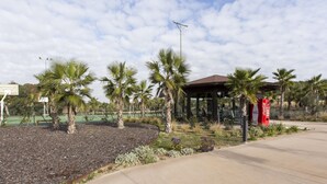 A sports court with palm trees, a covered seating area, and a Coca-Cola vending machine. - Golfside Luxury at Las Colinas (Orihuela Costa-Alicante)