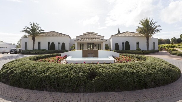 A modern building with a central courtyard, surrounded by neatly trimmed hedges and a paved walkway. - Golfside Luxury at Las Colinas (Orihuela Costa-Alicante)