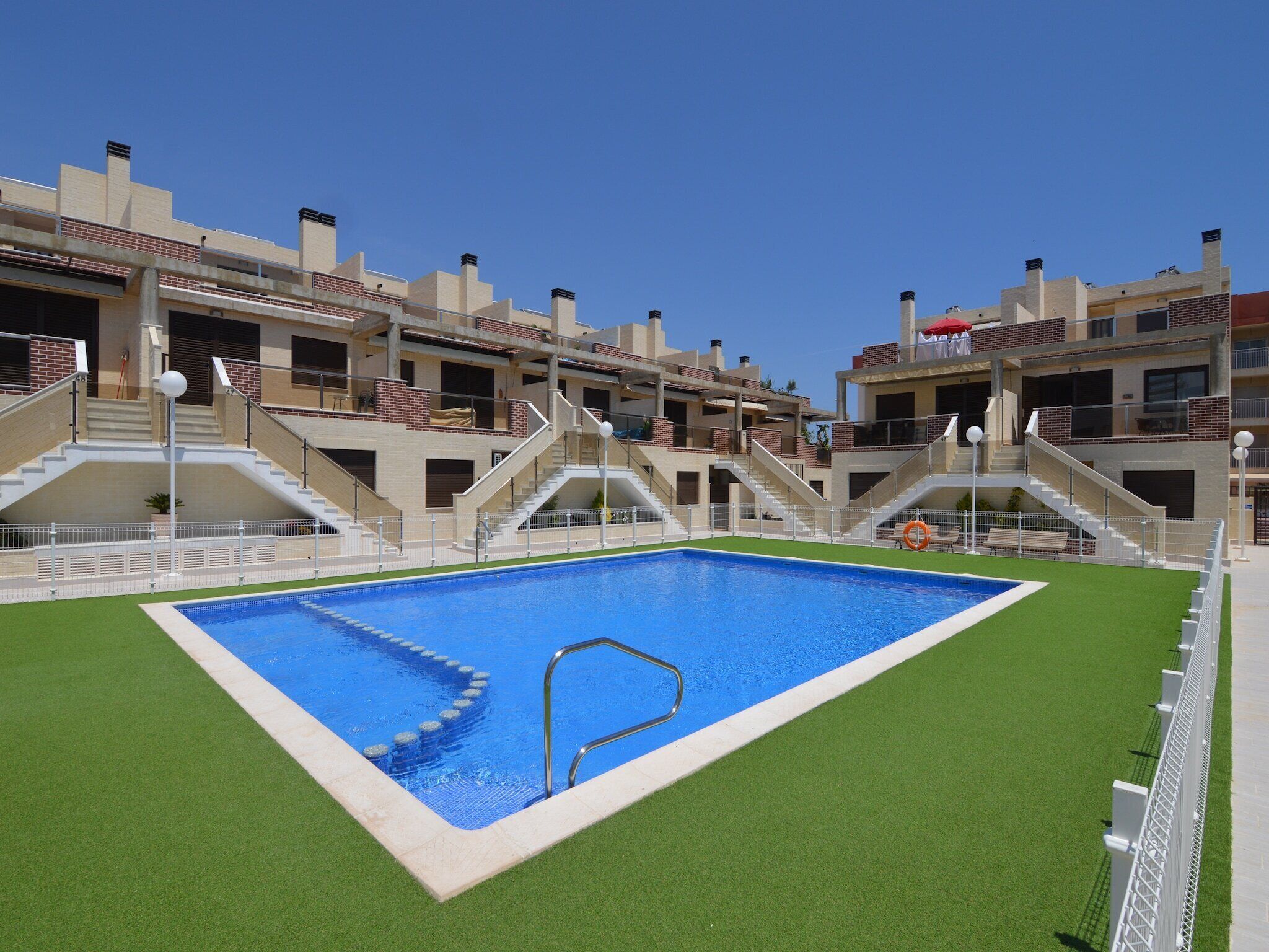 A swimming pool surrounded by a multi-story building with balconies and staircases.