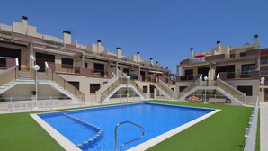 A swimming pool surrounded by a multi-story building with balconies and staircases.