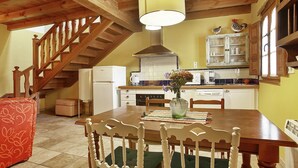 A dining area with a wooden table, chairs, and a vase with flowers. A staircase is visible in the background. - Mansion in Nava with Pool & Terrace (Nava - Asturias)