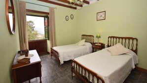 Un dormitorio con dos camas individuales, un escritorio, un espejo y una ventana con cortinas.