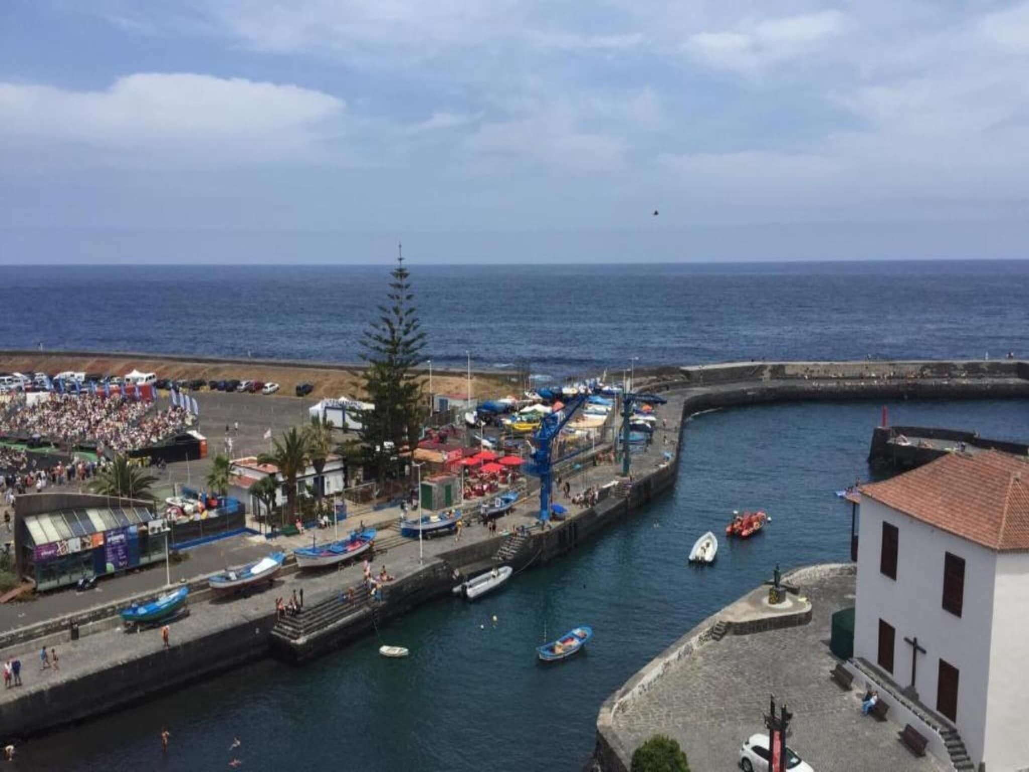 Un pueblo costero con un puerto deportivo, barcos y gente en un evento.