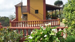 Un edificio amarillo con balcón rojo, escaleras y un patio.