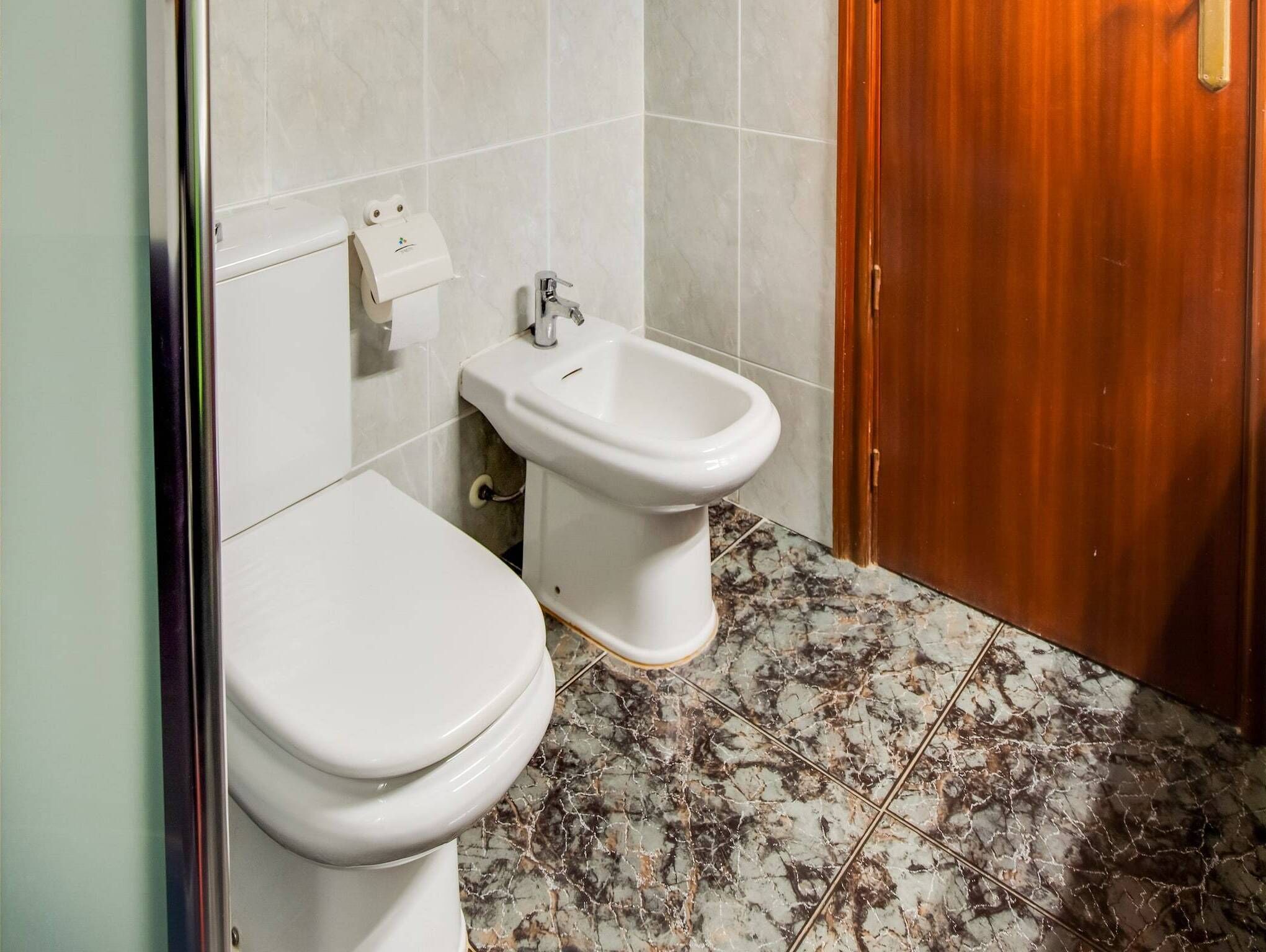 Un baño con inodoro, bidé y suelo de mármol.