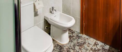 Un baño con inodoro, bidé y suelo de mármol.
