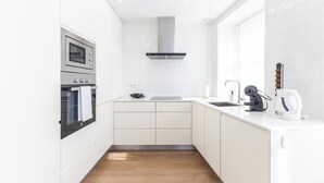A modern kitchen with white cabinetry, a stainless steel oven, a range hood, a sink, and a kettle. - Mexia Galvao - City Center, Mexia Galvão - City Center (Viana do Castelo)