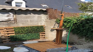 Una terraza de madera con estructura metálica, rodeada de grava y piedras para caminar.
