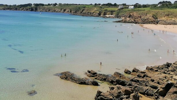 Una playa costera con costas rocosas y agua azul cristalina.