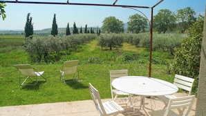 An outdoor patio with a table and chairs, surrounded by a garden and a view of the countryside. - Holiday Home in Béziers with Pool and Vineyard (Murviel les Béziers)