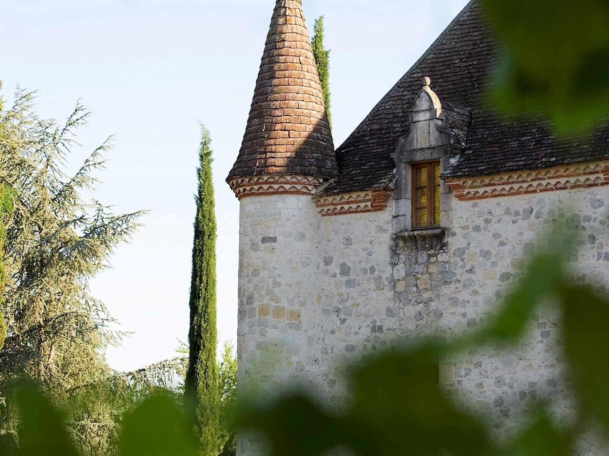 Ein historisches Gebäude mit einem Kegelturm und einem kleinen Fenster mit verziertem Rahmen.