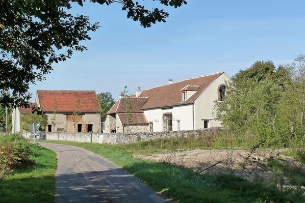 En landevej, der fører hen til en række traditionelle huse i sten og mursten med skrå tage.