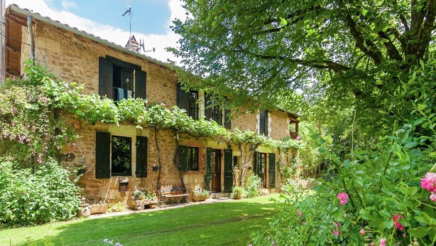 A stone building with a garden, a bench, and a pathway.