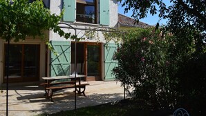 A two-story building with green shutters, a wooden door, and a window with a decorative arch. - Villa Overlooking Les Vans Centre (Les Vans)