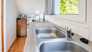 Een moderne keuken met twee roestvrijstalen spoelbakken, een koelkast en een koffiezetapparaat.