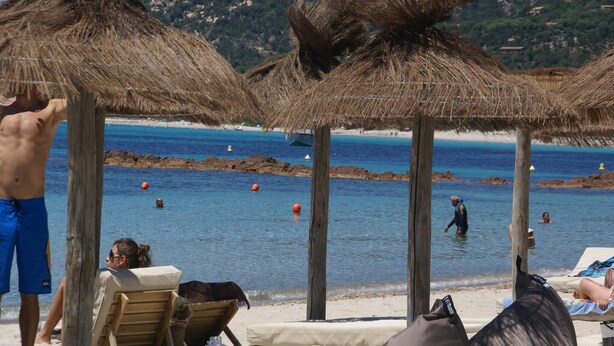 A beach with thatched umbrellas, wooden chairs, and lounge areas. - Holiday Home in Moriani-Plage near Beach (Moriani Plage)
