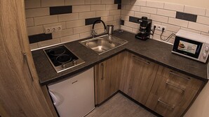 Une cuisine compacte avec des meubles de rangement en bois, une cuisinière encastrée, un évier et un four à micro-ondes.